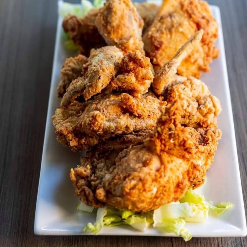 Crispy fried chicken pieces with lettuce garnish on a white rectangular plate.