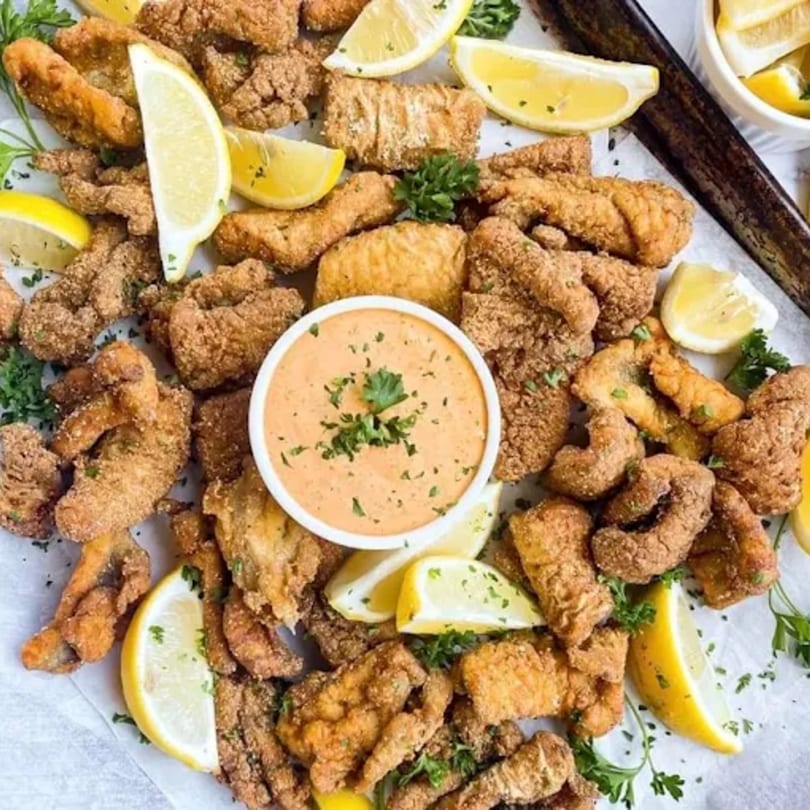 Shantell's fried catfish nuggets with lemon wedges, parsley, and a side of dipping sauce.