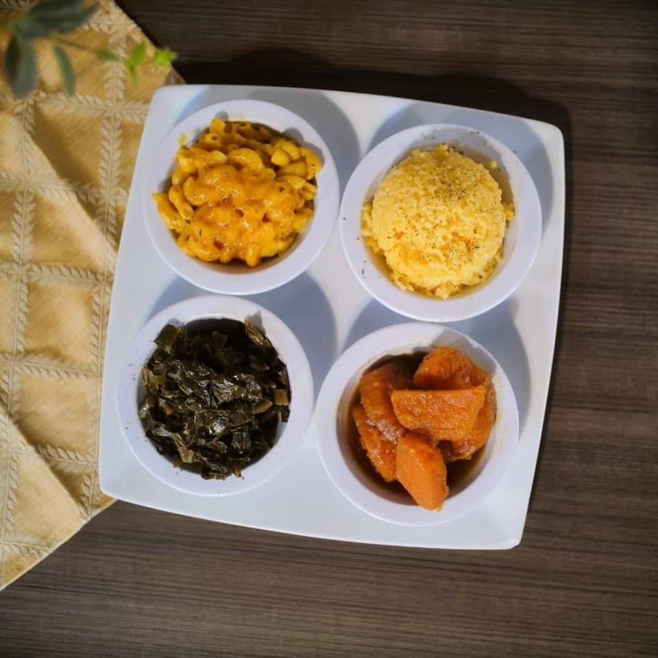 Four bowls of soul food sides: mac and cheese, mashed potatoes, collard greens, and candied yams.