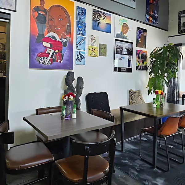 Interior of Shantell's Just Until Restaurant & Lounge, with tables, chairs, and vibrant artwork on the wall.